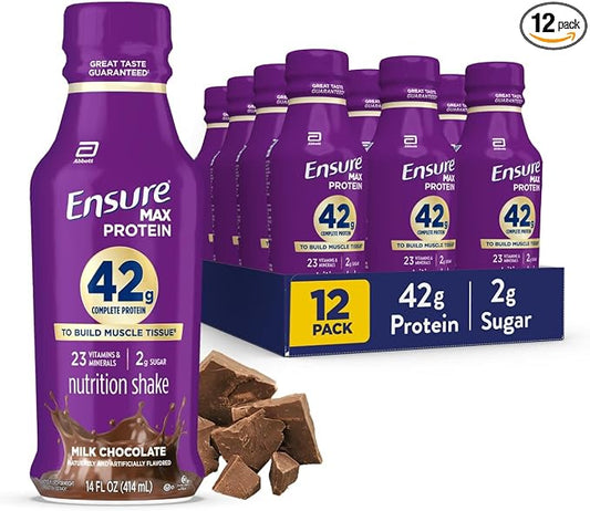 A 12-pack of Ensure Max Protein nutrition shake bottles in chocolate milk flavor, shown with one large bottle in front and a blue 12-pack carton behind. A small '12 pack' badge appears in the top right corner, and chocolate chunks are placed in front of the bottle.